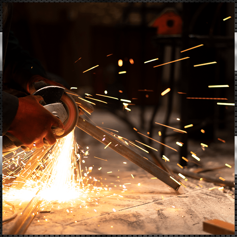 Close-up of worker using an angle grinder on metal, sparks flying.