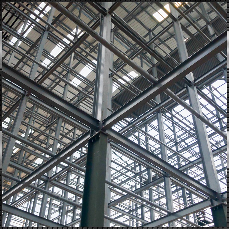 Structural steel framing in progress for a commercial building or warehouse, showcasing interconnected I-beams, girders, and steel columns during the steel erection phase—highlighting modern construction and engineering practices.