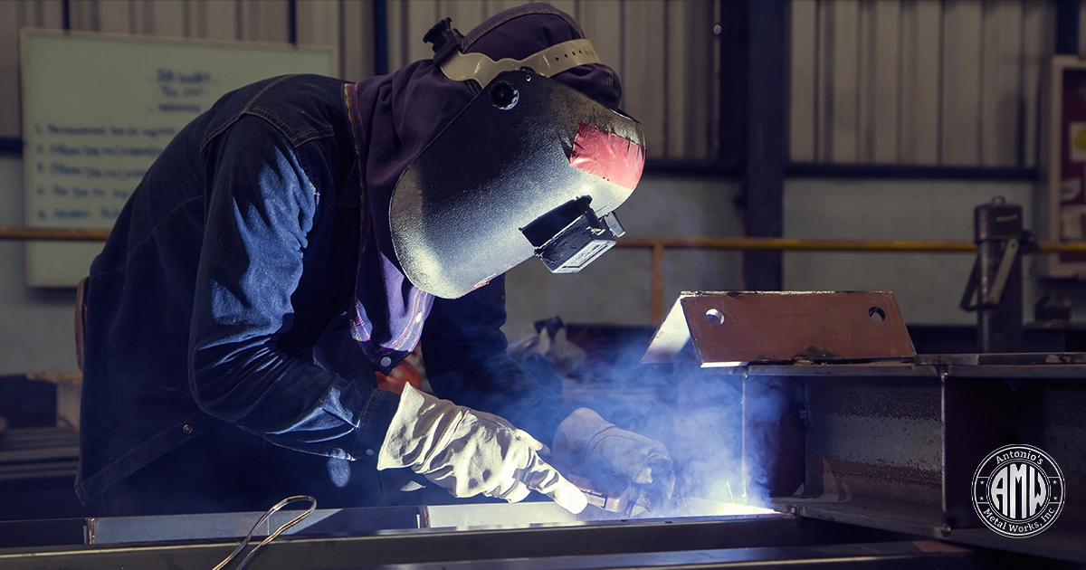Expert welder at Antonio's Metal Works, Inc. demonstrates custom steel fabrication by welding a large structural beam. This image highlights the company's professional welding and metalworking services for construction and custom projects.