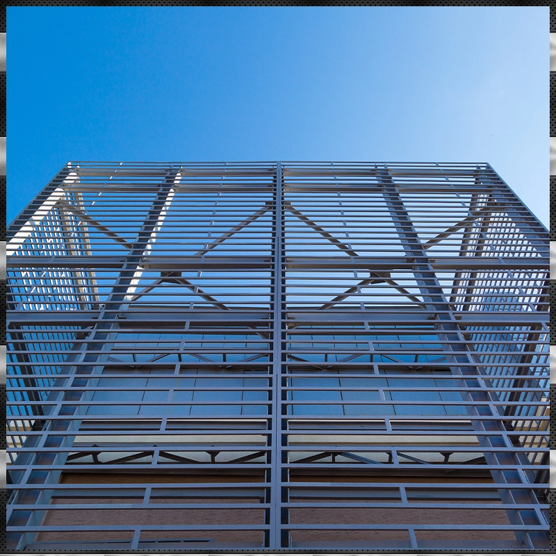 An low-angle outdoor shot of a modern building against a clear blue sky. The building features a prominent grid-like metal facade over large glass windows, creating a striking architectural pattern.