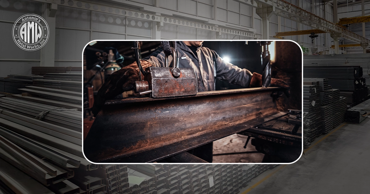 A welder wearing a mask and protective gloves works on a large, rusty metal beam in a workshop.
